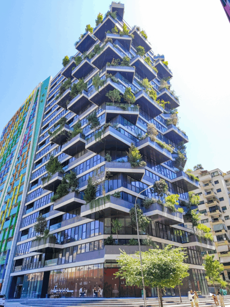 Ein modernes hohes Gebäude mit balkonähnlichen Plattformen auf denen Pflanzen und Bäume wachsen.